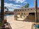 Community pool area with covered seating and palm trees under a bright blue sky at 624 Hawk Eye Dr, Apache Junction, AZ 85119