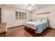 A light-filled bedroom with hardwood floors, plantation shutters, and a cozy bench at the bed's end at 6456 E Dallas St, Mesa, AZ 85205