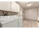 Well-lit laundry room with a washing machine, dryer, storage cabinets, and tiled floor at 6456 E Dallas St, Mesa, AZ 85205