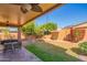 Lush backyard featuring a covered patio, a manicured lawn, and colorful flowering bushes at 7138 W Buckskin Trl, Peoria, AZ 85383