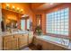 Bright bathroom featuring a soaking tub, vanity, and large glass block window for natural light at 7138 W Buckskin Trl, Peoria, AZ 85383