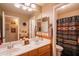 Bathroom featuring double sinks, a large mirror, and a separate toilet/shower area with decorative curtain at 7138 W Buckskin Trl, Peoria, AZ 85383