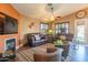 Comfortable living room featuring plush leather sofas, a cozy fireplace, and decorative ceiling fan at 7138 W Buckskin Trl, Peoria, AZ 85383