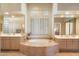 Bright bathroom with tile-trimmed tub, wood cabinets, dual sinks and shutters at 7848 E Parkview Ln, Scottsdale, AZ 85255