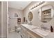 Elegant bathroom with a double sink vanity, granite countertops, and dual round mirrors above each sink at 8230 E Valley Vista Dr, Scottsdale, AZ 85250