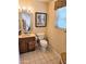 Bathroom with tiled floors, wood vanity, and a toilet beneath a window with blinds and floral print at 904 Leisure World --, Mesa, AZ 85206