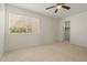 Bedroom features tan carpet, a ceiling fan, large window with blinds, and a walk-in closet at 11333 N 92Nd St # 2072, Scottsdale, AZ 85260