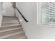 Carpeted stairway featuring a sleek, dark handrail, and a window providing natural light at 17339 W Paraiso Ln, Surprise, AZ 85387