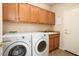 Convenient laundry room with wooden cabinets, washer, dryer, sink, and tiled flooring at 18123 W Hayden Dr, Surprise, AZ 85374