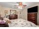 Bedroom featuring neutral walls, ceiling fan, a mirror, and a floral comforter on the wood bed frame at 19221 N Toya St, Maricopa, AZ 85138