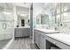Modern bathroom with gray cabinets, double sinks, framed mirrors, decorative tile accents, and glass enclosed shower at 20325 E Hummingbird Dr, Queen Creek, AZ 85142