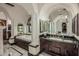 A bright bathroom showcases a marble floor, jacuzzi tub, arched columns, and dual vanity with black marble countertops at 20715 N 103Rd Pl, Scottsdale, AZ 85255