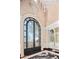 Elegant foyer with an arched glass door with black trim, crystal chandelier, and marble flooring at 20715 N 103Rd Pl, Scottsdale, AZ 85255