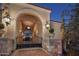 Elegant gated entrance with ornate ironwork, lush greenery, and sconce lighting, creating a grand arrival at 20715 N 103Rd Pl, Scottsdale, AZ 85255