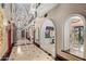 Elegant hallway with arched doorways, marble flooring, chandeliers, and access to various rooms at 20715 N 103Rd Pl, Scottsdale, AZ 85255