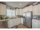 Well-lit kitchen with stainless steel refrigerator and white cabinets, offering ample storage space and a clean aesthetic at 2206 S Ellsworth Rd # 50B, Mesa, AZ 85209
