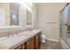 Bathroom featuring double sinks, wood cabinets and a tiled shower with a glass door at 22722 N 120Th Ln, Sun City, AZ 85373