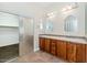 Bathroom featuring double sinks with wooden cabinets and a walk-in shower at 22722 N 120Th Ln, Sun City, AZ 85373