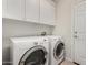 Functional laundry room with white washer and dryer, complemented by overhead cabinets for storage at 26485 W Yukon Dr, Buckeye, AZ 85396
