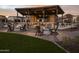 Outdoor fire pit lounge area with Adirondack chairs, lights, and beautiful mountain views at sunset at 3294 W Storm Cloud St, San Tan Valley, AZ 85144