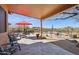 Covered patio with stone flooring overlooking a fenced pool area, seating, and desert landscape at 43638 N 22Nd St, New River, AZ 85087