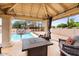 Covered outdoor seating area with a fireplace, chairs, and a view of the pool for relaxation and entertainment at 7820 S Maple Ave, Tempe, AZ 85284