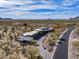 Stunning aerial shot of desert home, showcasing the home's design, long driveway, and natural surroundings at 8145 E Tecolote Cir, Scottsdale, AZ 85266
