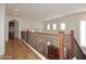Bright hallway with hardwood floors and decorative iron railing on stairway to the lower level at 9901 E Bahia Dr, Scottsdale, AZ 85260