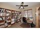 Spacious home office featuring built-in bookshelves, a ceiling fan, and a desk with a computer setup at 9901 E Bahia Dr, Scottsdale, AZ 85260