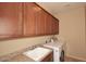 Functional laundry room with overhead cabinets, a sink with countertop, and a modern washing machine at 9901 E Bahia Dr, Scottsdale, AZ 85260
