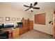 Bright home office with ceiling fan, and wooden cabinets, desk, and neutral walls and flooring at 9901 E Bahia Dr, Scottsdale, AZ 85260
