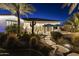 A landscaped yard featuring lush landscaping, a cactus, stone pavers and elegant lighting at dusk at 10417 N 180Th Dr, Waddell, AZ 85355