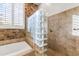 Bathroom featuring a shower with glass block and a bathtub area at 10417 N 180Th Dr, Waddell, AZ 85355