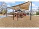 Community playground features slides and play equipment under a shade canopy on woodchips at 10417 N 180Th Dr, Waddell, AZ 85355