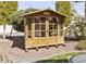 Backyard wooden shed with glass windows, nestled among mature trees and offering ample storage at 10417 N 180Th Dr, Waddell, AZ 85355