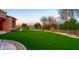 Expansive backyard features lush green turf, mature trees, and desert landscaping creating a serene outdoor space at 12160 E Whispering Wind Dr, Scottsdale, AZ 85255