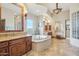 Bright bathroom featuring tiled flooring, soaking tub, dual vanities, and elegant lighting at 12160 E Whispering Wind Dr, Scottsdale, AZ 85255