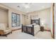 Bright bedroom with light-colored carpeting, shuttered windows, wooden bed frame, and cozy armchair at 12160 E Whispering Wind Dr, Scottsdale, AZ 85255