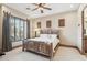 Cozy bedroom featuring a rustic bed frame, ceiling fan, and scenic window at 12160 E Whispering Wind Dr, Scottsdale, AZ 85255