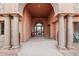 Grand entryway with stone columns, an ornate wrought-iron door, and elegant desert landscaping at 12160 E Whispering Wind Dr, Scottsdale, AZ 85255