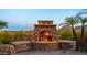 Close-up of outdoor fireplace constructed with detailed stonework; framed by desert flora and open sky at 12160 E Whispering Wind Dr, Scottsdale, AZ 85255