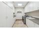 Spacious laundry room with ample storage cabinets, countertop space, stainless washer and dryer, and tiled floor at 12160 E Whispering Wind Dr, Scottsdale, AZ 85255