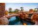 Inviting pool with stone bridge, rock features, waterfall, and outdoor fireplace for a luxurious backyard oasis at 12160 E Whispering Wind Dr, Scottsdale, AZ 85255