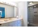 Bathroom featuring a vanity with ample storage and a step-in shower with glass block for natural light at 13623 N 108Th Dr, Sun City, AZ 85351