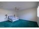 Bright bedroom with green carpet, ceiling fan, and natural light from window with white plantation shutters at 13623 N 108Th Dr, Sun City, AZ 85351