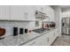 Close-up of kitchen features, including granite countertops, white subway tile backsplash, and stainless steel appliances at 14360 W Windrose Dr, Surprise, AZ 85379