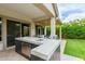 An outdoor kitchen featuring a marble countertop island and seating for four, perfect for entertaining in style at 14360 W Windrose Dr, Surprise, AZ 85379