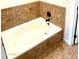 Bathroom featuring a built-in tub with tan tile surround and stylish black hardware at 1440 E Grove Ave, Mesa, AZ 85204