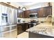 Beautiful kitchen with stainless steel appliances, granite countertops, dark wood cabinets, and tile flooring at 16416 W Rock Springs Ln, Surprise, AZ 85374