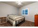 Neutral bedroom has a large window with shutters, ceiling fan, and classic quilt bedspread at 17507 W Fetlock Trl, Surprise, AZ 85387